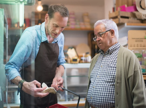 Ein Mann mittlerwen Alters und ein älterer Herr schauen sich im Supermarkt einen Pilz an.