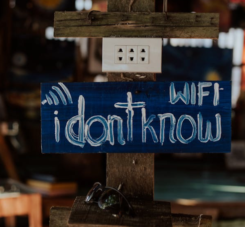 Ein Bild mit einem Holzschild auf dem "WIFI I dont know" steht